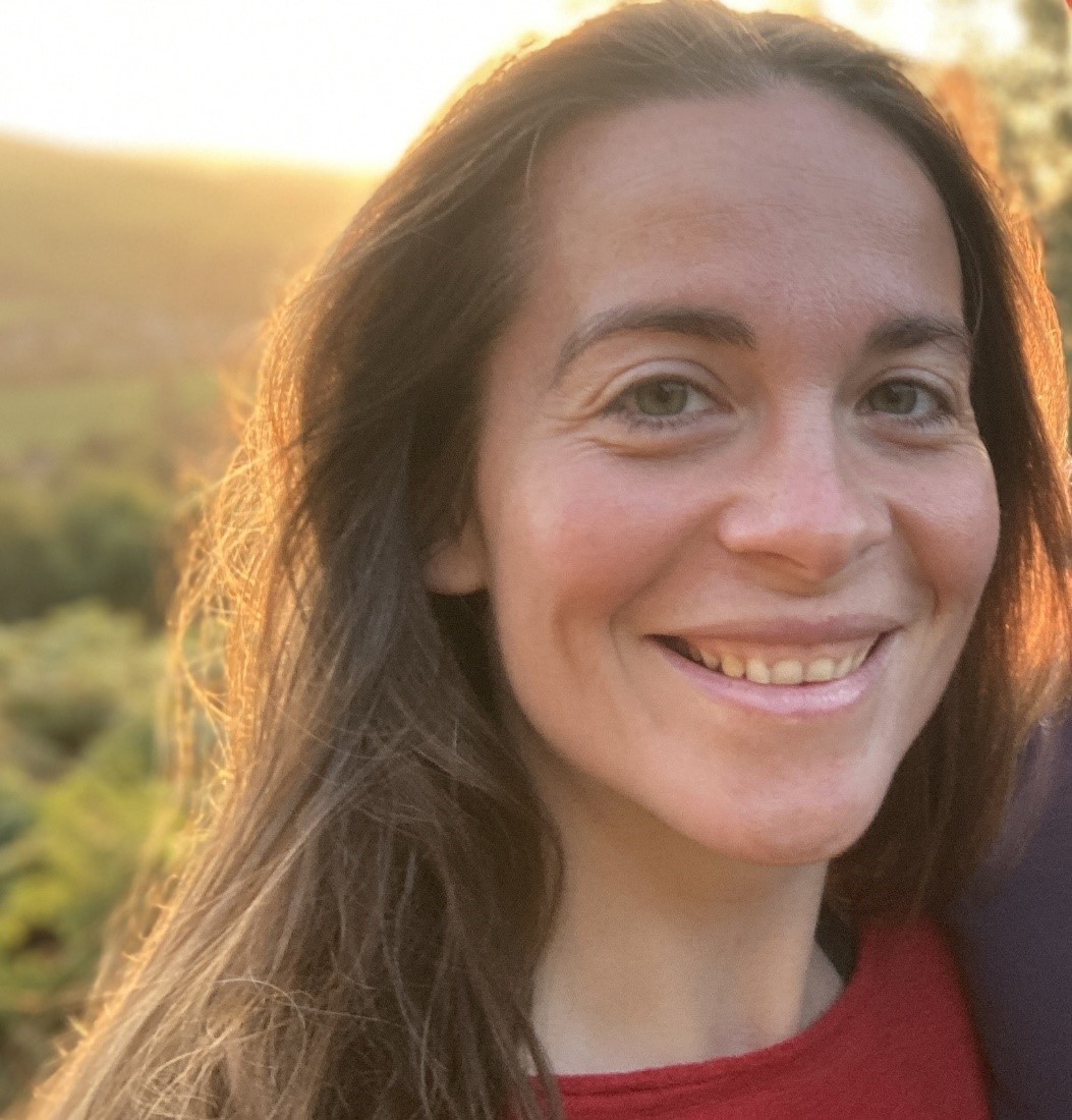 Woman smiling at camera with sun behind